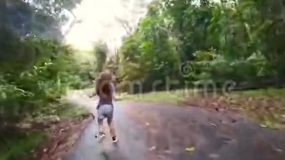 一个小女孩在绿色的大自然中间的道路上奔跑视频的预览图