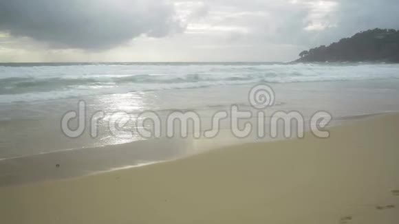热带沙滩的风景泡沫形成的波浪在海滨和雨云在天空视频的预览图
