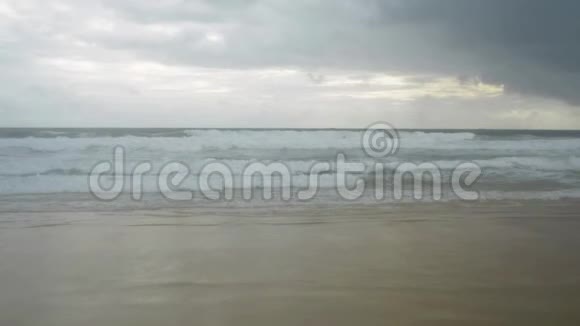 热带沙滩的风景泡沫形成的波浪在海滨和雨云在天空视频的预览图