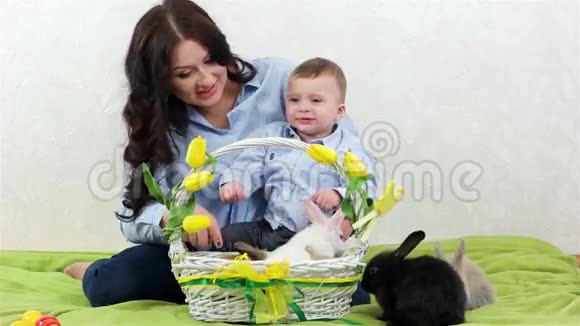 妈妈和儿子一起玩年轻的妈妈和孩子坐在一起幸福的家庭柳条篮子里的兔子视频的预览图