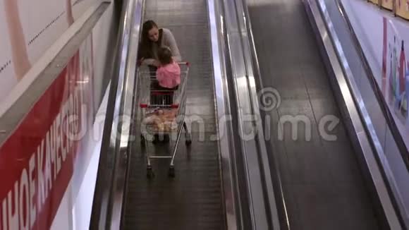 母亲带着戴格乘坐无轨电车坐自动扶梯到商店中心的下一层视频的预览图