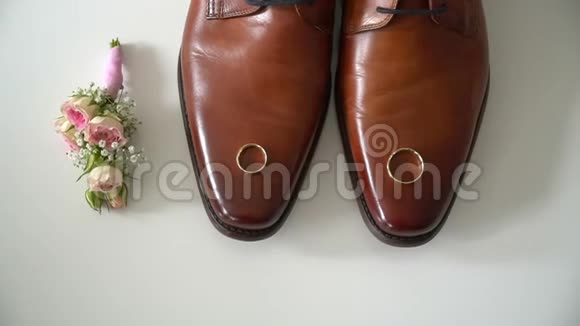 结婚戒指躺在棕色的鞋子上视频的预览图