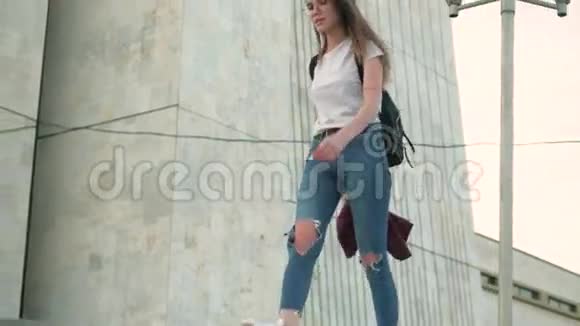 穿着眼镜和破牛仔裤的布鲁内特女孩在城市里走来走去视频的预览图