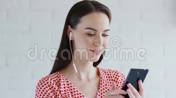可爱的女人听音乐和使用智能手机视频的预览图
