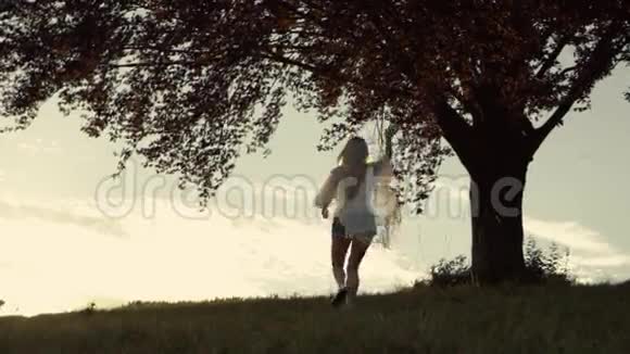 穿着boho外观的运动女孩跑到这棵不寻常的树触摸它日落视频的预览图