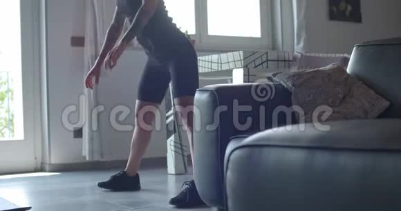 年轻的纹身女人在家里做健身运动前做伸展运动客厅里做家庭训练4公里视频的预览图