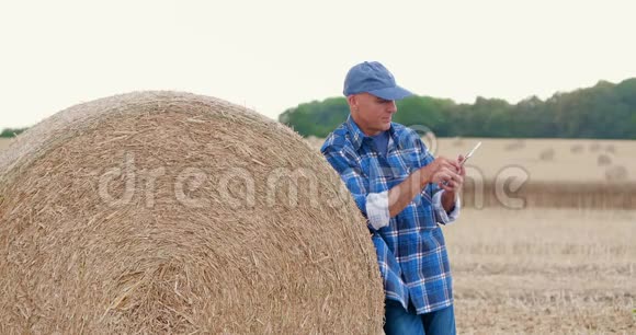 农民用数码平板电脑站在干草堆上视频的预览图