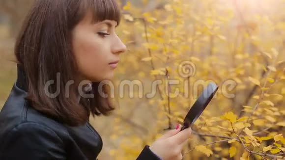 女人在树叶上透过放大镜视频的预览图