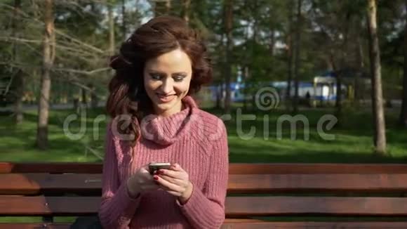 春季阳光明媚的日子里一个女少女坐在长椅上打电话镜头来自普罗尔斯视频的预览图