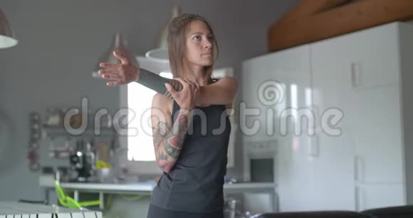 年轻的纹身女人在家里做健身运动前热身客厅家政培训4k视频的预览图