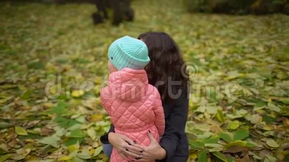 妈妈带着孩子在秋天公园快乐的年轻妈妈和小女孩在秋天的森林里休息慢动作视频的预览图