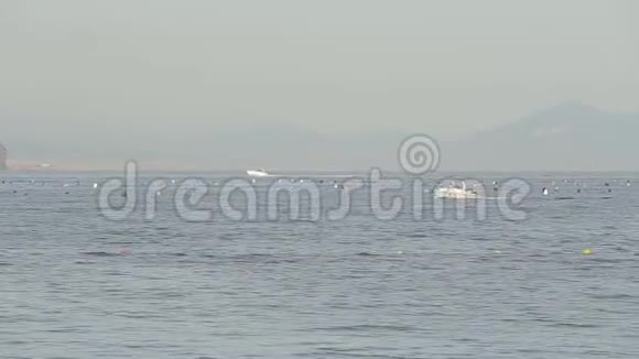 一艘小船沿着大海航行在一个有山的岛屿的背景上视频的预览图