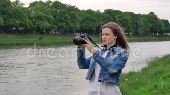 风雨交加美女游客在河边用专业相机拍摄视频视频的预览图