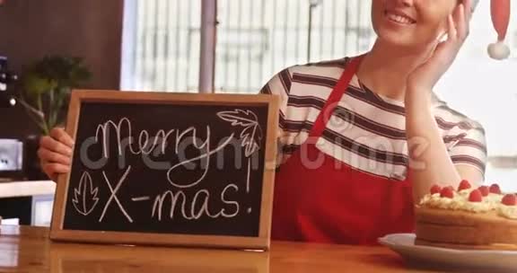 咖啡厅拿着印有圣诞快乐标志的石板的女服务员视频的预览图