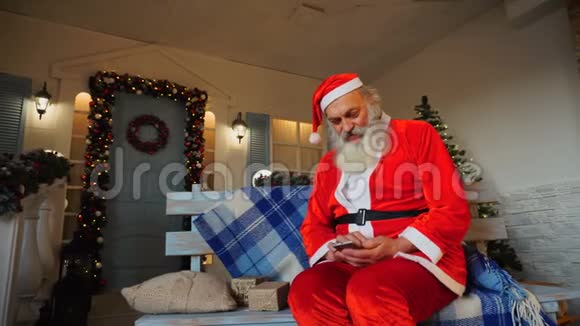 快乐的圣诞老人通过智能手机祝贺假期视频的预览图