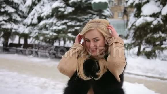 一个穿着毛皮大衣的女孩在雪地公园的肖像视频的预览图