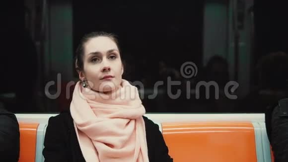 坐在地铁里的年轻体贴的女人的肖像女孩用公共交通工具环顾四周看着窗户视频的预览图