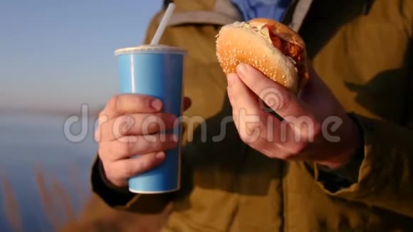 一个饥饿的人拿着一个美味的汉堡包和一杯苏打水慢动作1920x1080全高清视频的预览图