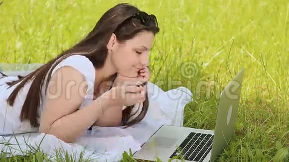 户外草地上有笔记本电脑的女孩视频的预览图