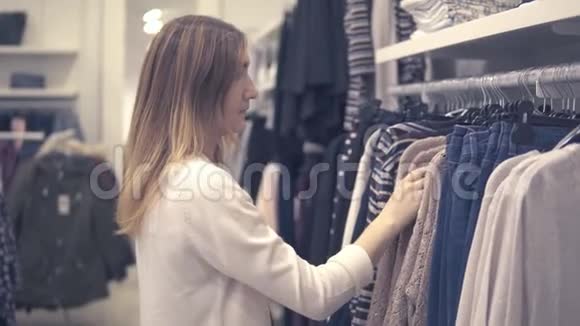 年轻的美女在时尚商场购物挑选新衣服视频的预览图