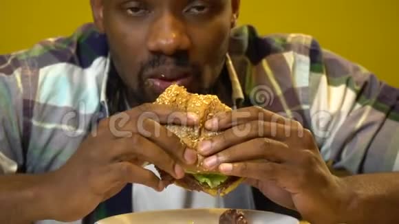 非裔美国人面部表情滑稽在咖啡馆特写镜头里吃汉堡视频的预览图