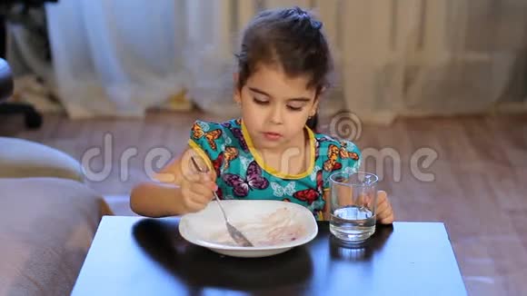 女孩一边吃一边分心小女孩吃粥看着他视频的预览图