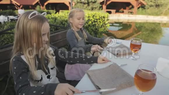 孩子们坐在户外咖啡馆的桌子旁视频的预览图