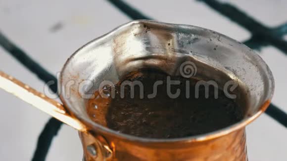 在一个铜制的土耳其煮黑咖啡然后在煤气炉上煮咖啡师在家附近准备热饮视频的预览图