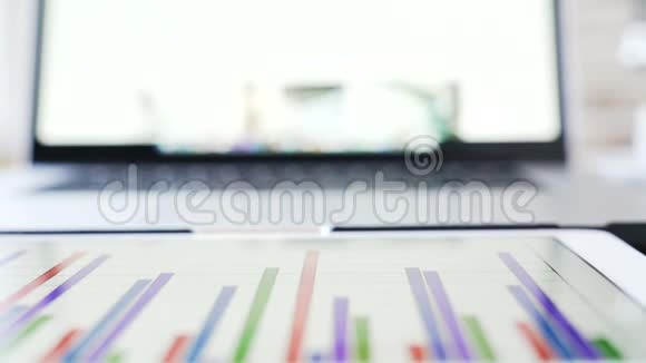 商人的工作场所屏幕上有金融信息的笔记本电脑和平板电脑视频的预览图