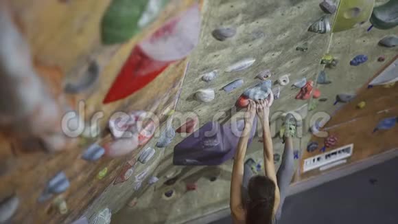 年轻女子攀岩者正在室内攀岩健身房攀岩苗条漂亮的女人做一些艰难的动作视频的预览图