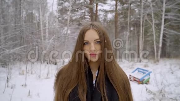 在雪地背景下的冬季公园里一位时尚的年轻美女在户外散步特写了这幅画是的视频的预览图