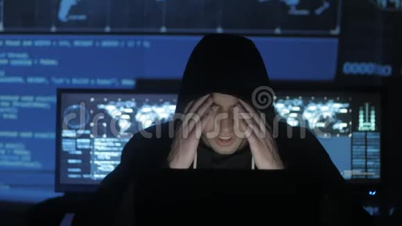 一个在电脑上工作过度的黑客在充满显示器的网络安全中心感到头疼视频的预览图