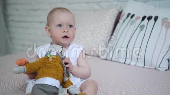 一个漂亮的小女孩正在床上玩一只柔软的玩具兔子视频的预览图
