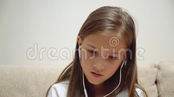 戴着耳机听音乐的小女孩坐在沙发上视频的预览图