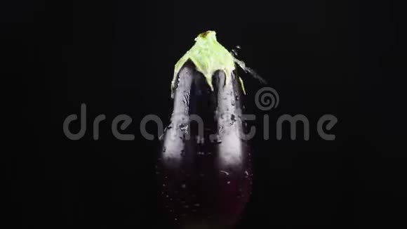 茄子特写水滴落在黑色背景上旋转的苹果上超级慢动作视频的预览图