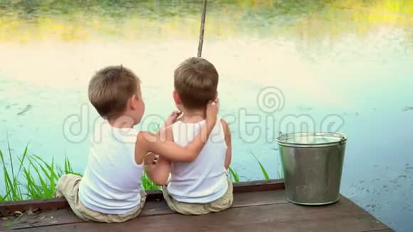 男孩子们穿着白色的裙子钓鱼美丽的孩子们在湖面上的夏天玩得很开心视频的预览图