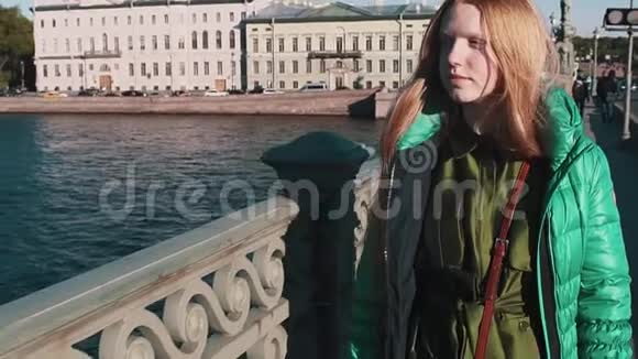 长着长发的姜姑娘穿过城市的河桥视频的预览图