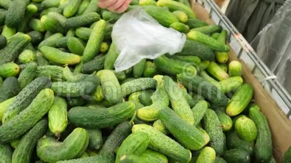 一个女人在蔬菜货架上的超市里买蔬菜和水果男人选择黄瓜慢动作4k视频的预览图