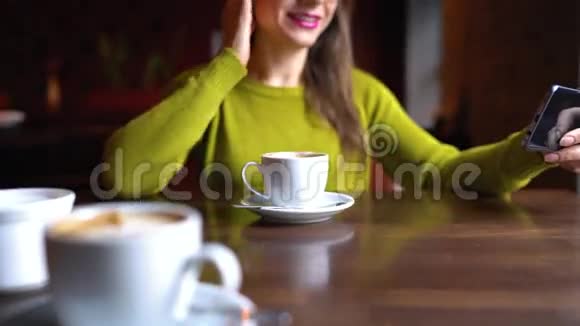 女人在Skype上聊天或在咖啡馆里领导智能手机上的直播视频的预览图