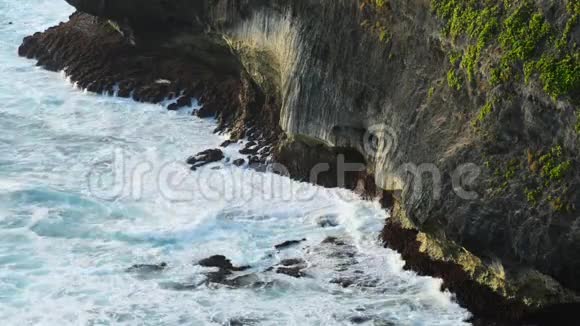 波浪撞击热带海滩上的岩石形成飞溅的形状强大的波浪在岩石海滩上著名的乌卢瓦图神庙视频的预览图