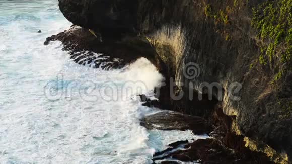 波浪撞击热带海滩上的岩石形成飞溅的形状强大的波浪在岩石海滩上著名的乌卢瓦图神庙视频的预览图