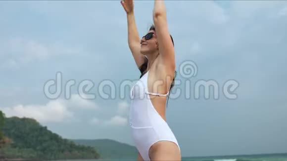穿着白色泳衣在热带海滩摆姿势的快乐美女视频的预览图