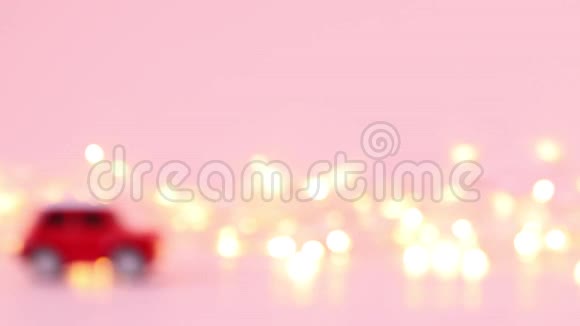 红色儿童玩具车和粉红色背景上的金色闪烁花环交付概念视频的预览图