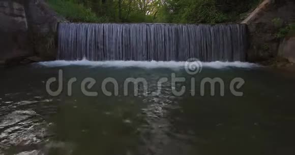 森林边缘河流上小瀑布的鸟瞰图视频的预览图