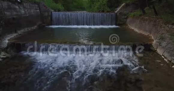 森林边缘河流上小瀑布的鸟瞰图视频的预览图