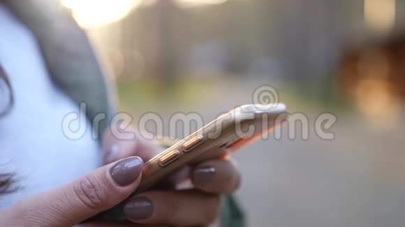 女孩手里拿着手机在日落背景上特写带着模糊慢动作1920x1080全高清视频的预览图