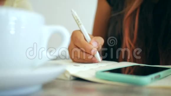 一个女人坐在咖啡店里写日记的特写镜头高清慢行视频的预览图
