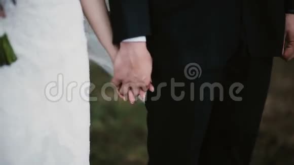 婚礼上新郎新娘牵手的特写镜头穿着婚纱的女人靠近男人拿着花束视频的预览图