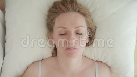 一个躺在床上的女人睁开眼睛微笑特写镜头从上面看视频的预览图