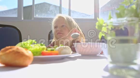小金发女郎坐在餐桌旁妈妈给果汁饮料视频的预览图